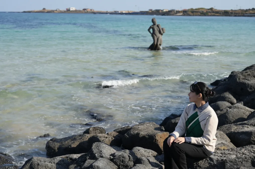제주도 바람 속에 부드럽게 흔들리는 은빛 억새와 푸른 바다의 해안 풍경