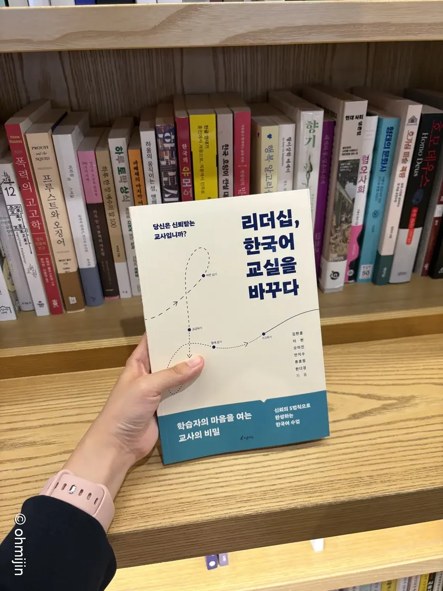 서점 책장에서 리더십, 한국어 교실을 바꾸다 책 한 권을 손으로 꺼내고 있는 감성 클로즈업 실물 사진